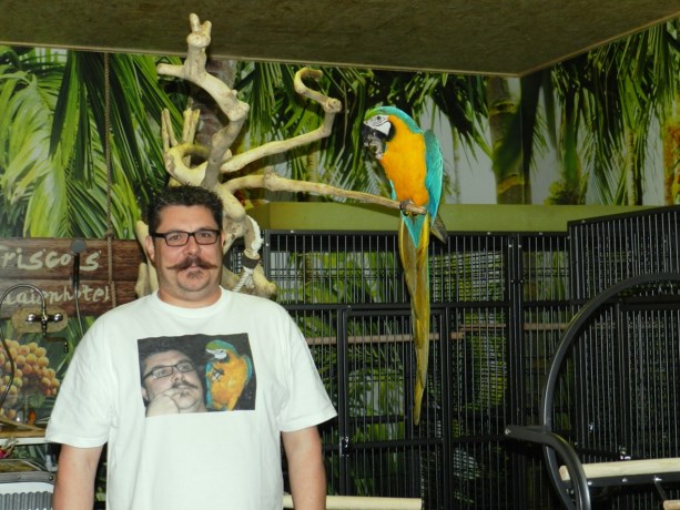 Крис Шарлье и сине-желтый ара Фриско в отеле для попугаев