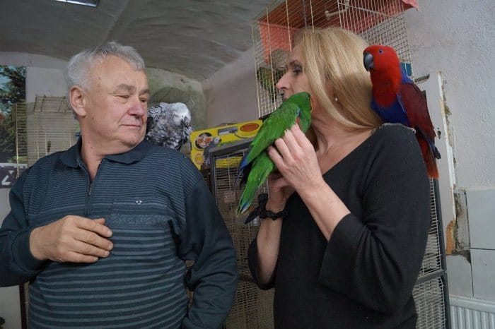 Ханс-Юрген Фенглер с жако на плече и помощницей с двумя попугаями в своем приюте