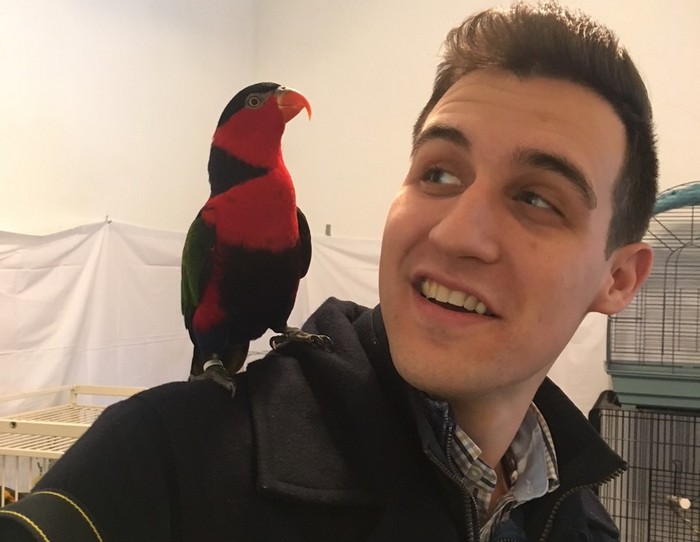 Журналист с дамским широкохвостым лори на плече в приюте для попугаев